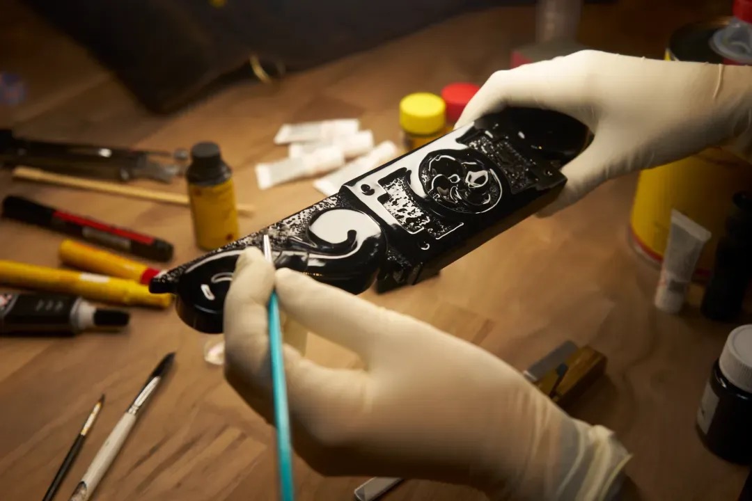 Oberflächenarbeit an einem schwarzen Zierteil in der PIANOHOF-Werkstatt